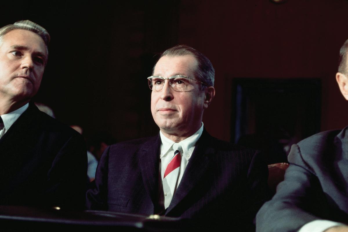 Haynsworth, flanked by two other men, looks out and away