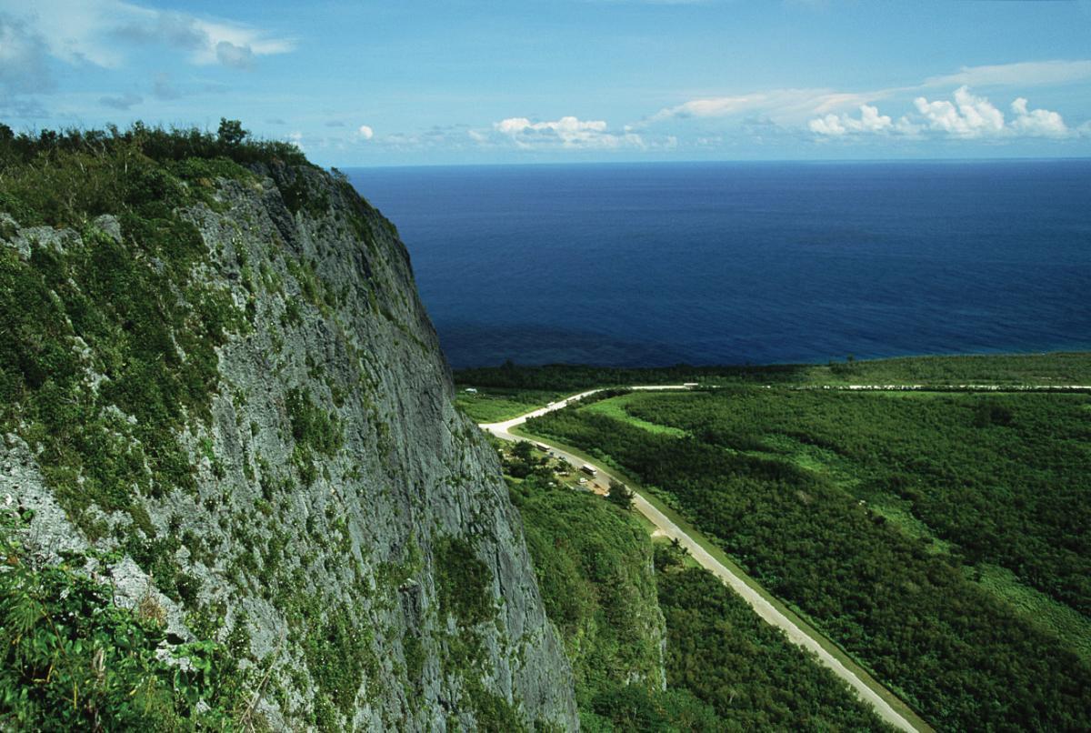 Photograph of a cliff, empty highway, with ocean in the background