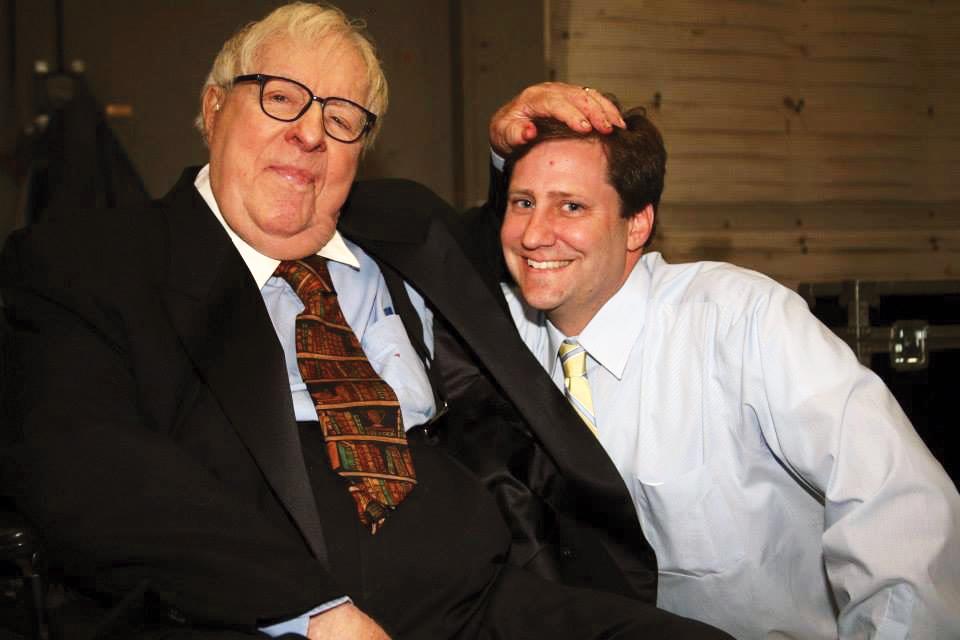 Photograph of two men, one has his hand on the head of the other