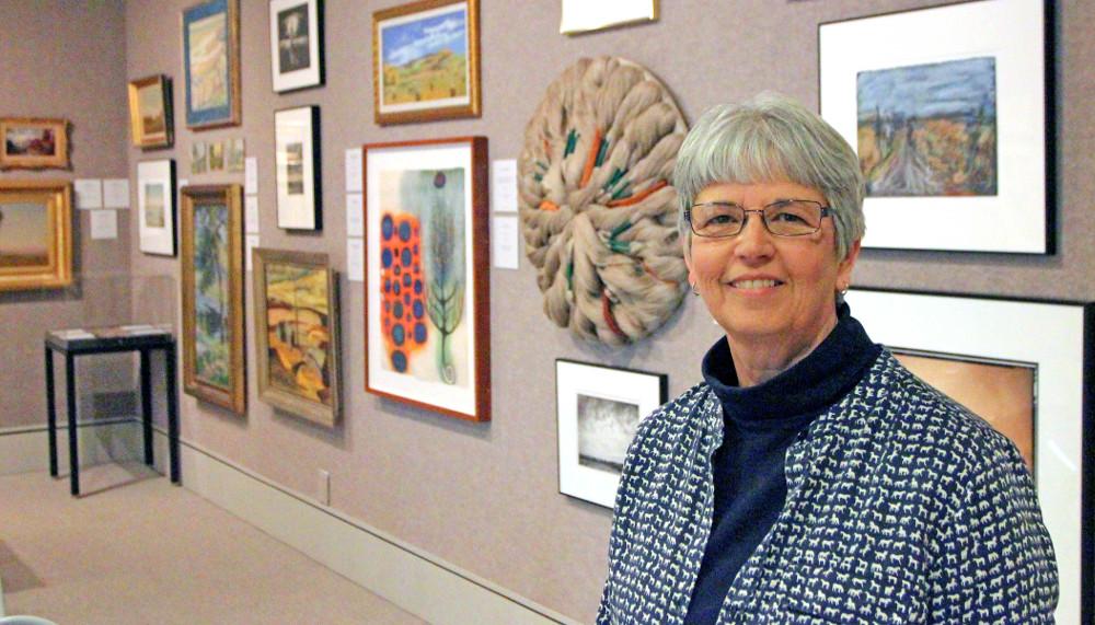 woman standing in front of wall of framed art