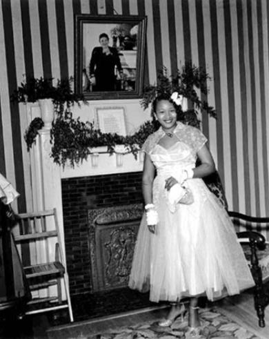 Unidentified woman posing before a portrait of Lela Walker, Lela Walker Clubhouse, undated.