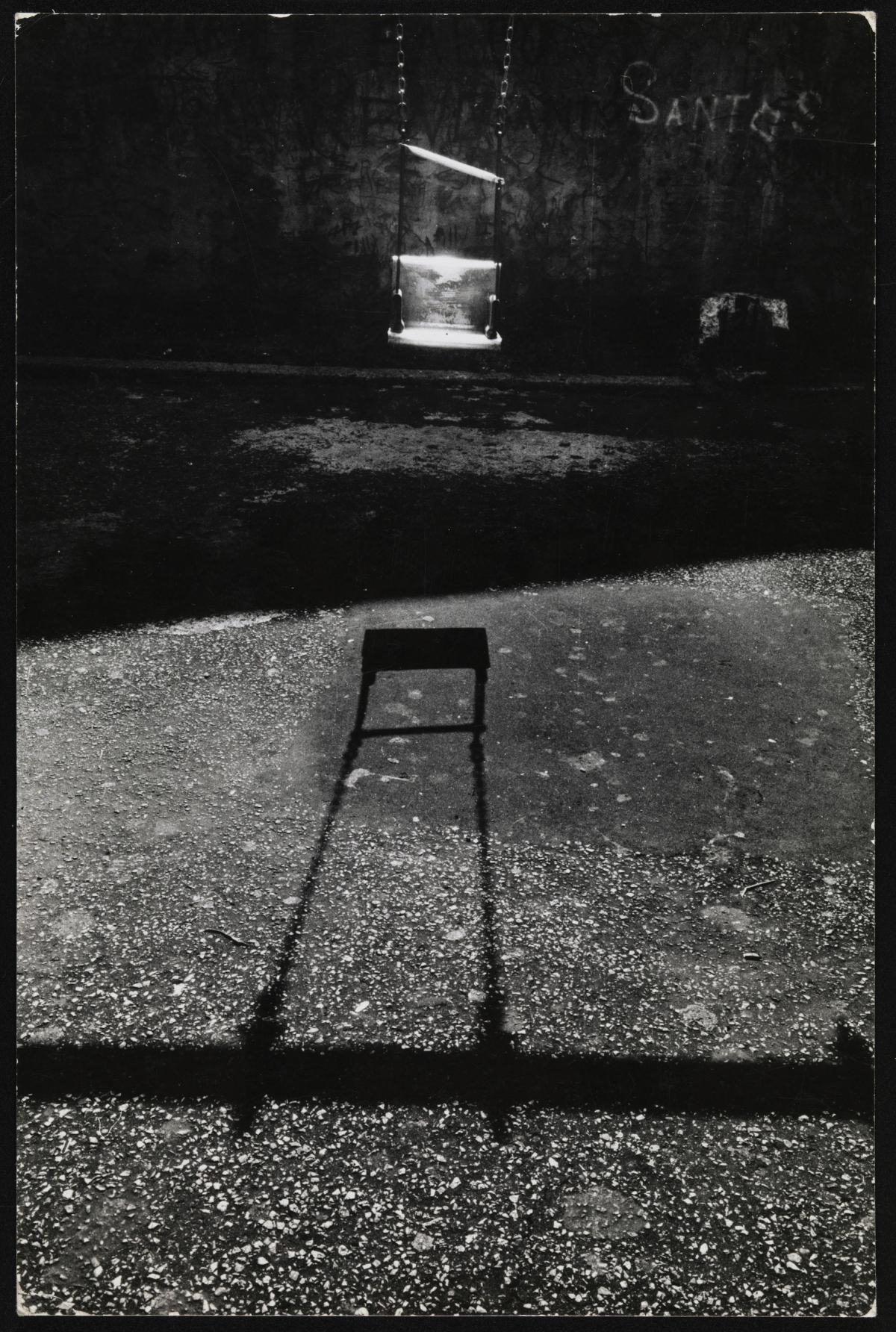 Sunlight provides dramatic lighting in this photo of a metal swing in a city playground by Louis Draper