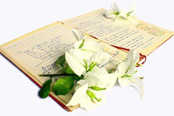 Photo of an open book of poetry, with a bunch of lilies laid on top of the book