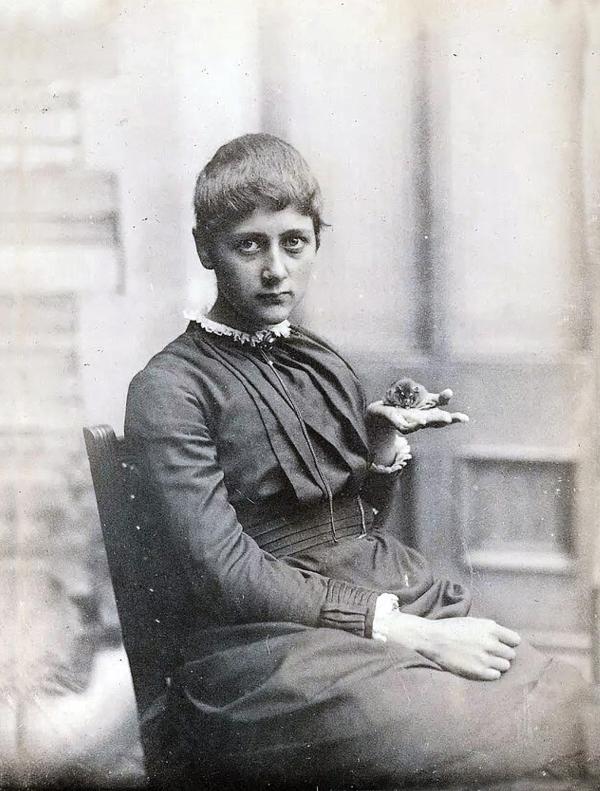 Photograph of Beatrix Potter as a young woman holding a mouse.