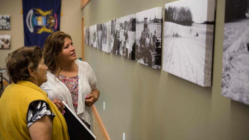 Two women looking at black and white photos on wall