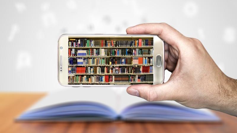 Hand holding a smartphone, whose screen displays a full bookshelf