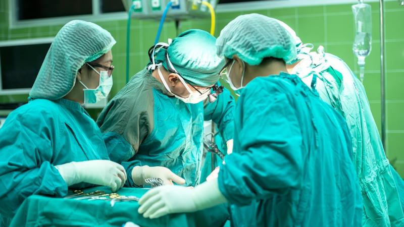 Several surgeons in green scrubs, participating in an operation