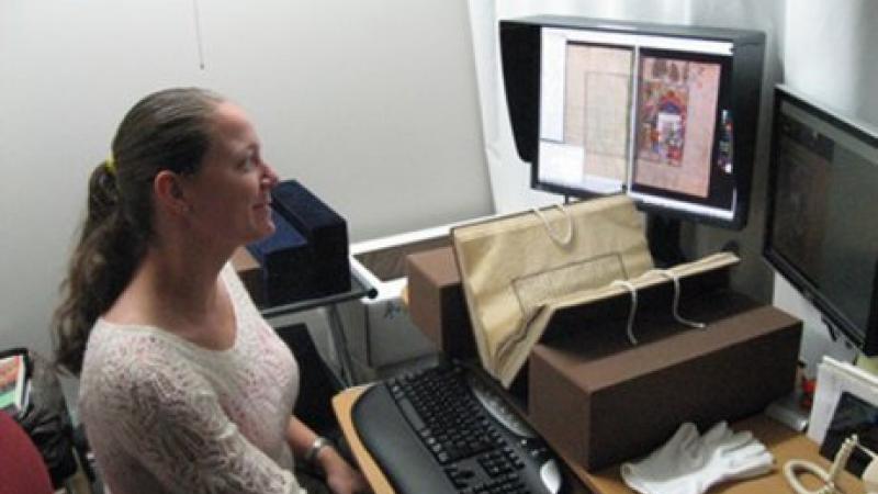 A woman working in front of a computer, smiling.