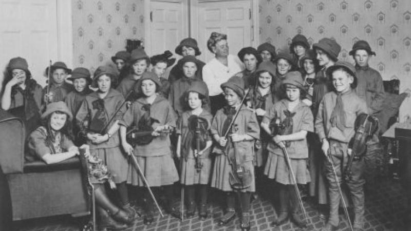 black and white photo of children holding violins