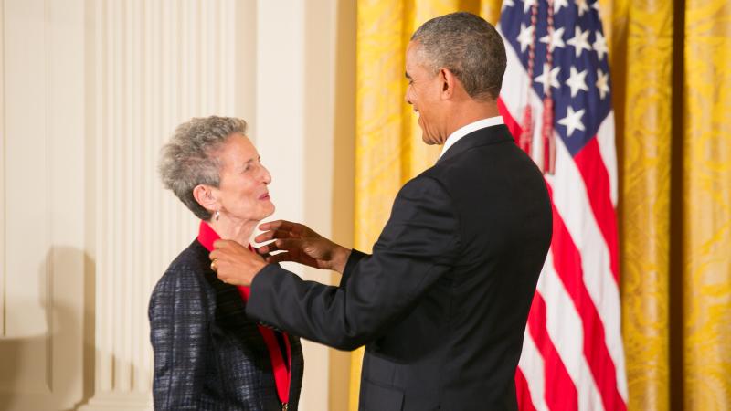 President Barack Obama places a red-ribboned medal on the neck of Natalie Zemon Davis.