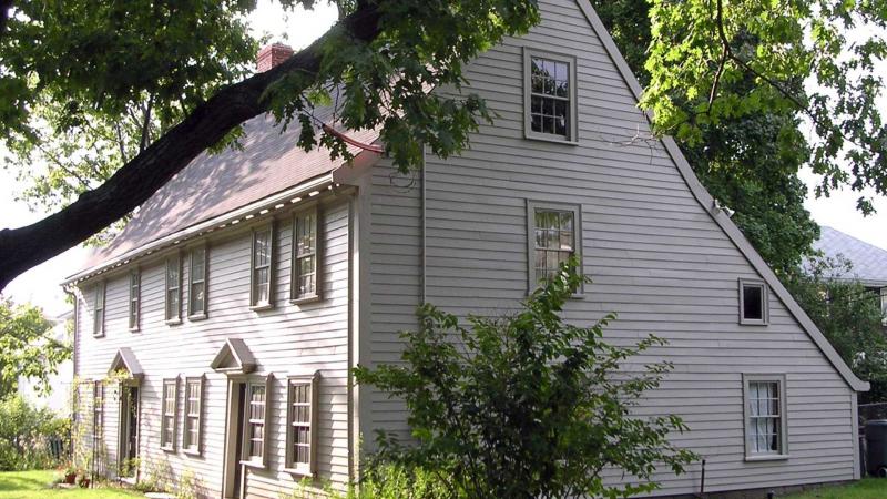 Image of white wooden Historic New England home with a tree in the foreground