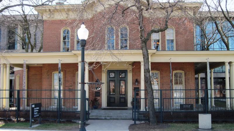 Image of Jane Addams Hull House, a brick building with a porch and large windows.