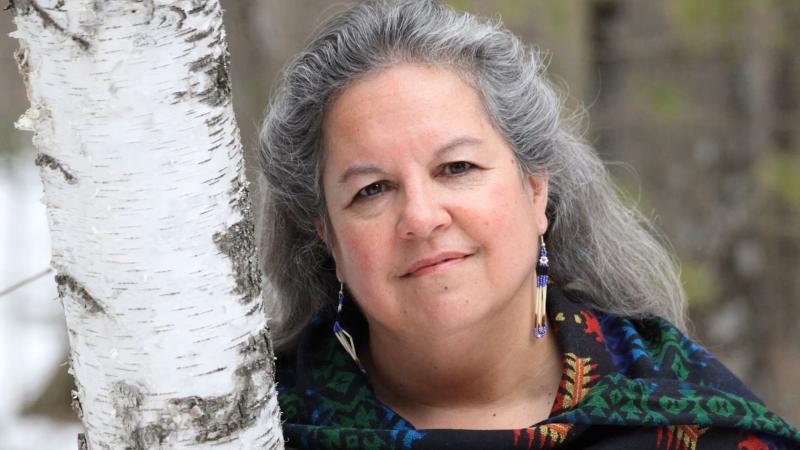 Photo of Robin Wall Kimmerer leaning against a tree