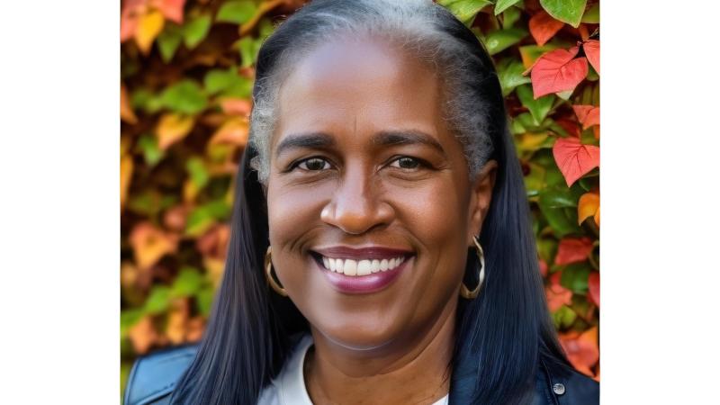 Robin Harris in a leather jacket, autumnal leaves changing color in the background